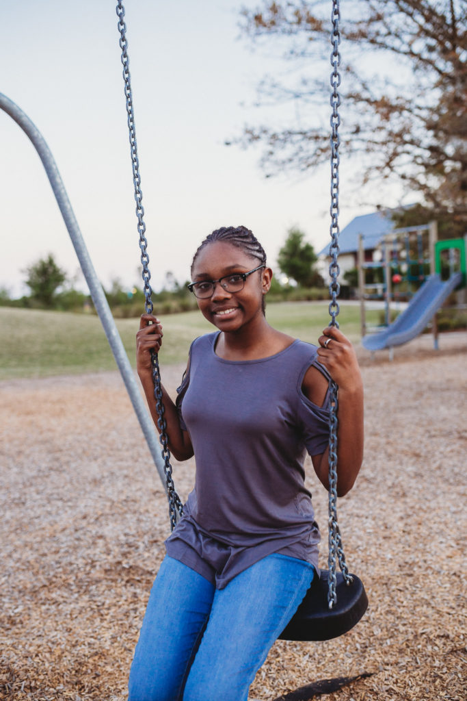 girl in grey shirt sitting on swing